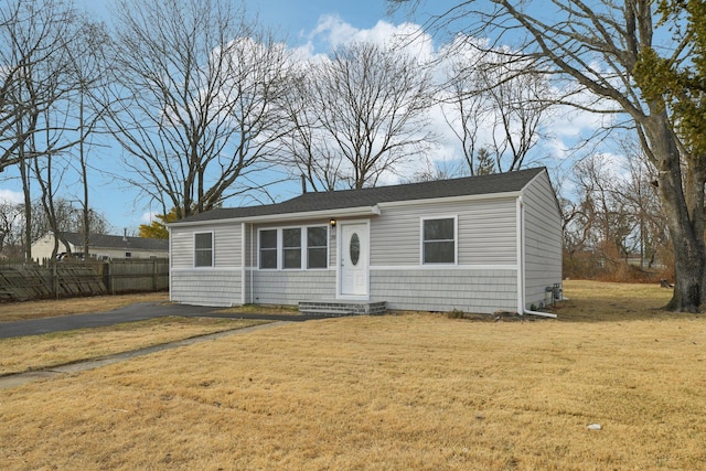 view of front of house with entry steps, a front lawn, and fence