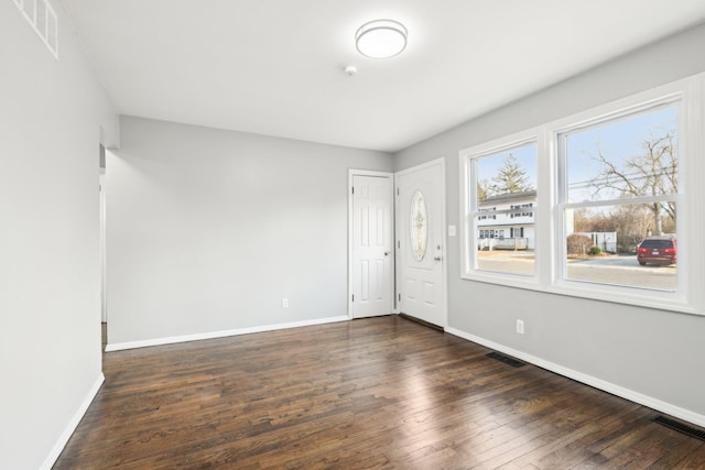 spare room featuring dark wood finished floors, visible vents, and baseboards