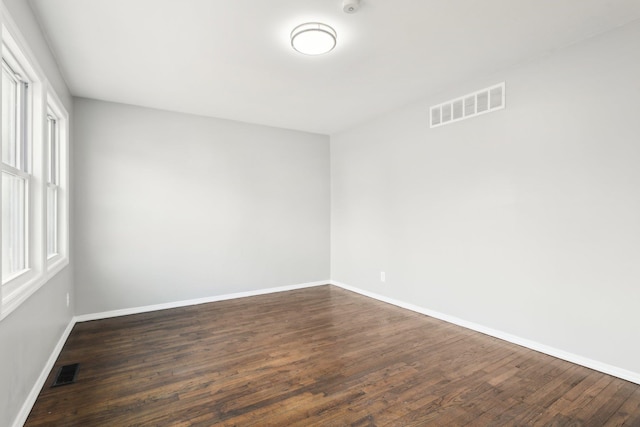 unfurnished room featuring visible vents, baseboards, and dark wood-style flooring