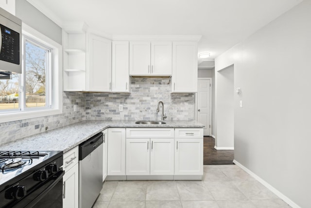 kitchen with a sink, light stone countertops, dishwasher, and white cabinets