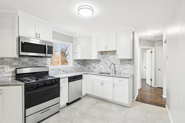 kitchen with light stone countertops, white cabinetry, stainless steel appliances, and a sink