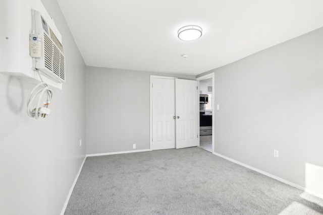 carpeted empty room with a wall mounted air conditioner and baseboards