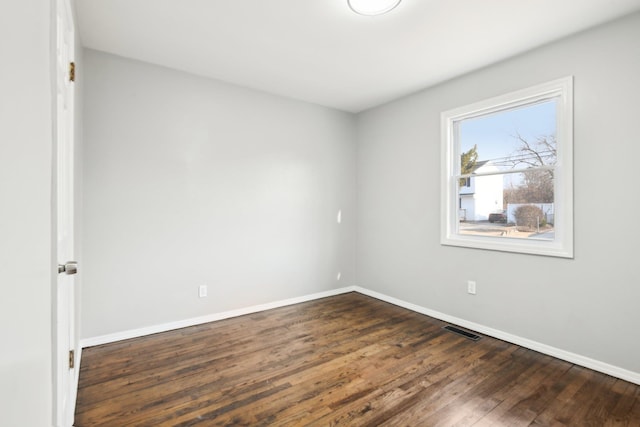 unfurnished room with dark wood finished floors, visible vents, and baseboards