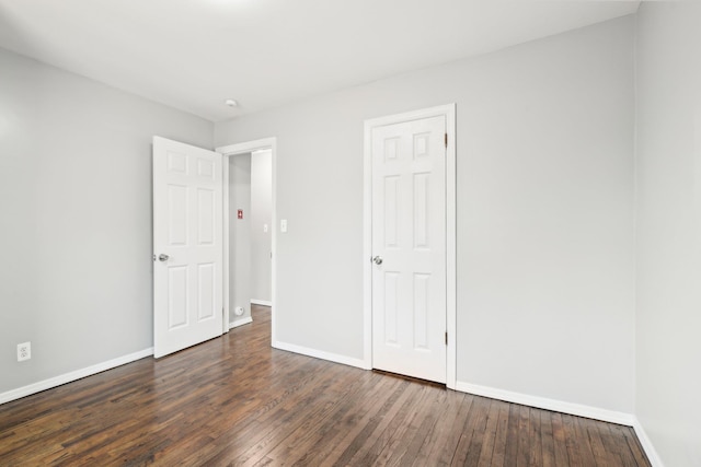 unfurnished bedroom with baseboards and dark wood-style flooring