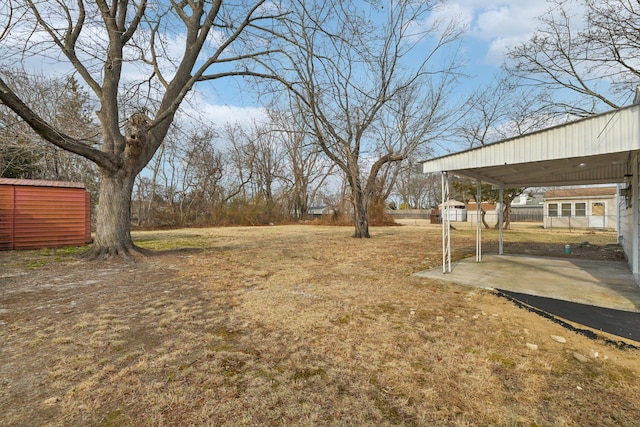 view of yard with driveway, an outbuilding, a shed, and fence