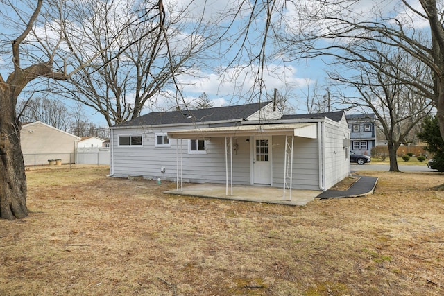 rear view of property featuring a patio area, a yard, and fence