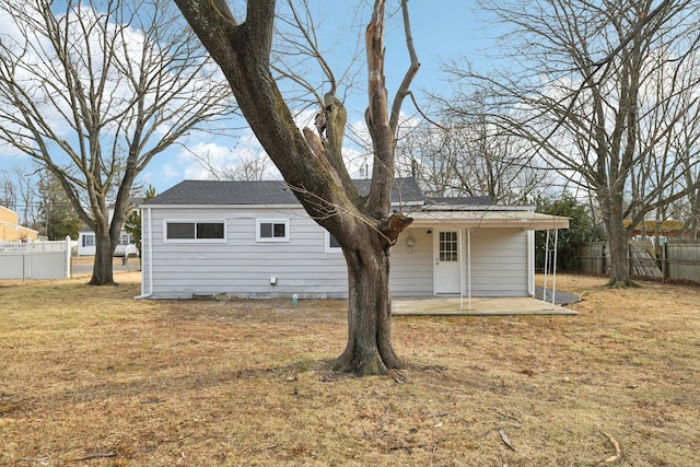 rear view of property featuring a yard, a patio, and fence