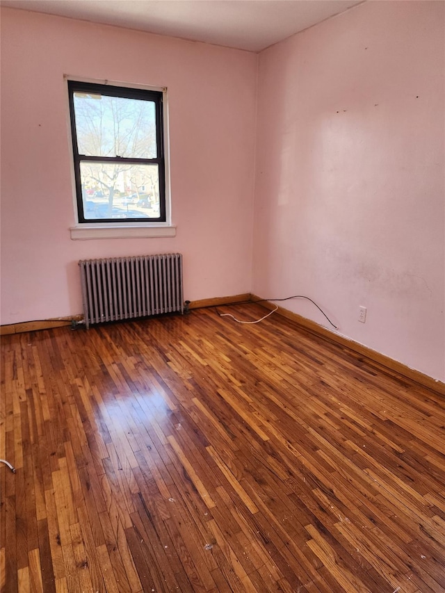 unfurnished room featuring hardwood / wood-style flooring and radiator