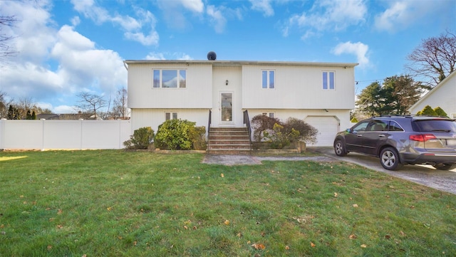 split foyer home featuring concrete driveway, a garage, fence, and a front lawn