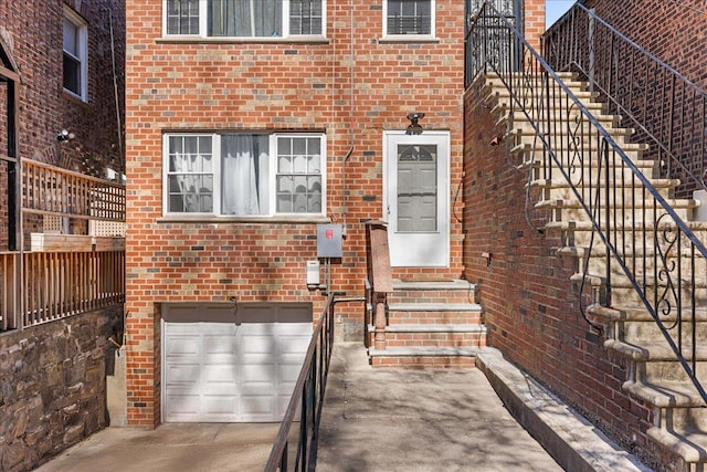 entrance to property featuring brick siding, an attached garage, and concrete driveway