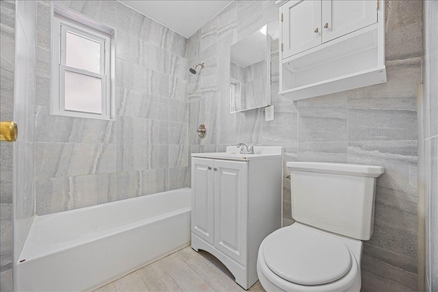 full bathroom with vanity, shower / bathing tub combination, toilet, and tile walls