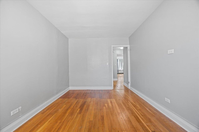 spare room with baseboards and hardwood / wood-style floors