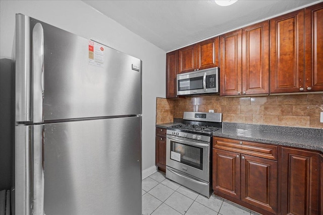 kitchen featuring light tile patterned floors, tasteful backsplash, dark countertops, and appliances with stainless steel finishes