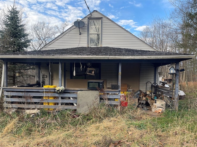 rear view of property featuring roof with shingles and covered porch