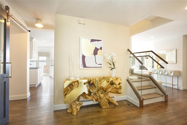 interior space with visible vents, baseboards, a barn door, and wood finished floors