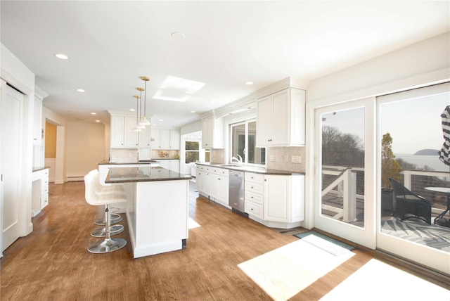 kitchen featuring a sink, light wood-type flooring, a kitchen island, and white cabinetry