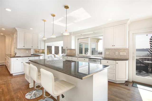 kitchen with dark wood-type flooring, white cabinets, a healthy amount of sunlight, and a kitchen island