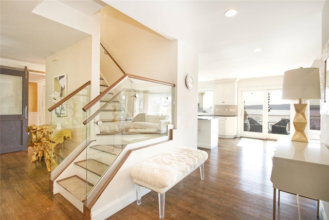 stairway featuring recessed lighting, a barn door, and wood finished floors