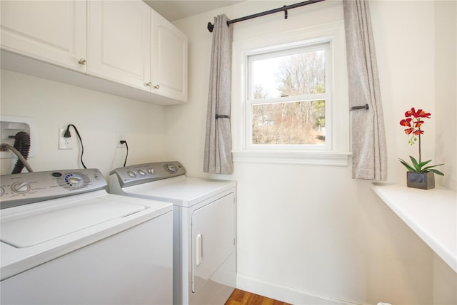 clothes washing area with washer and dryer, wood finished floors, cabinet space, and baseboards