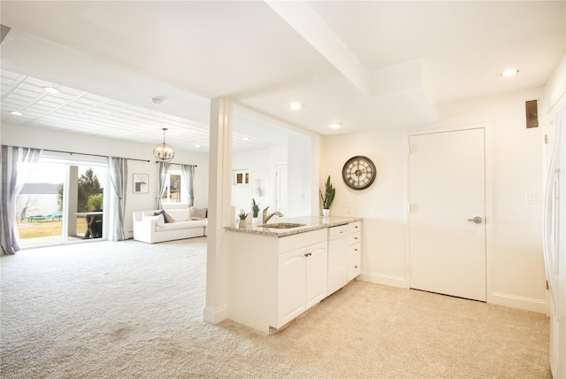 kitchen featuring visible vents, light carpet, light stone counters, white cabinets, and a sink