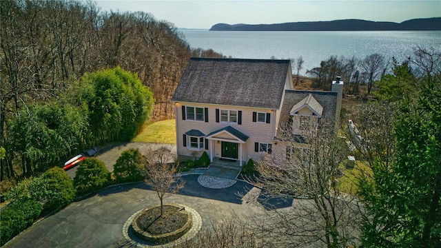 view of front of property with a water view, driveway, and a chimney