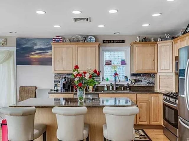 kitchen featuring a sink, stainless steel appliances, visible vents, and light brown cabinetry