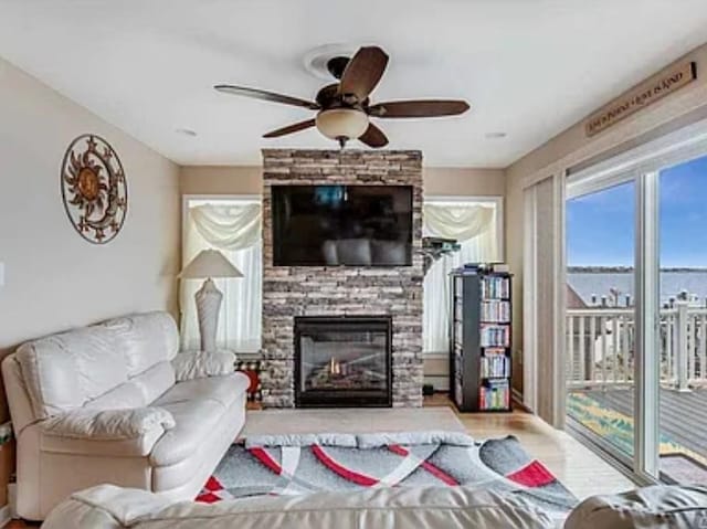 living area with ceiling fan and a fireplace