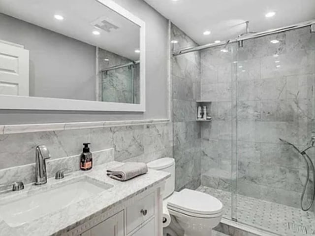 bathroom featuring toilet, a stall shower, recessed lighting, tile walls, and vanity