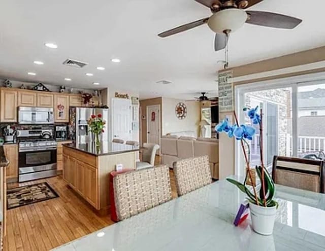 kitchen featuring visible vents, light wood-style flooring, appliances with stainless steel finishes, dark countertops, and a center island