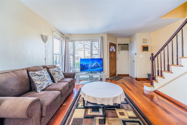 living area featuring stairway, a wall mounted AC, baseboards, and hardwood / wood-style flooring