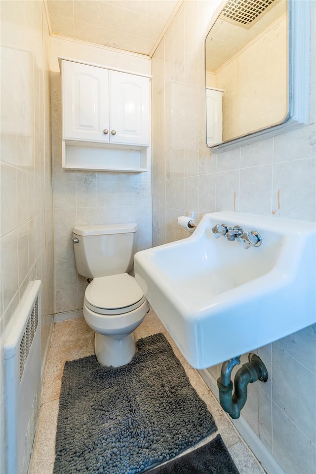 bathroom with toilet, tile walls, radiator, and a sink