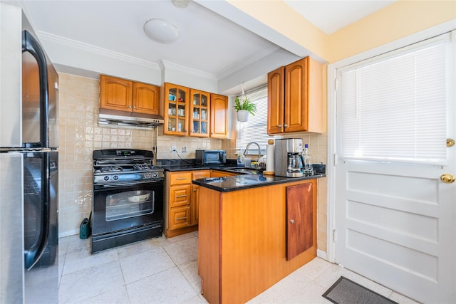 kitchen featuring a sink, black appliances, glass insert cabinets, under cabinet range hood, and brown cabinets