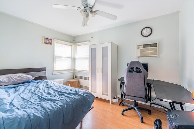 bedroom featuring radiator, an AC wall unit, light wood-type flooring, and ceiling fan