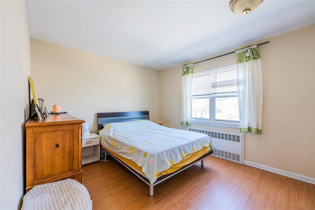 bedroom featuring light wood-type flooring, radiator heating unit, and baseboards