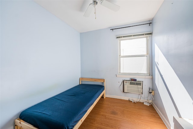 bedroom with baseboards, wood finished floors, a ceiling fan, and a wall mounted AC