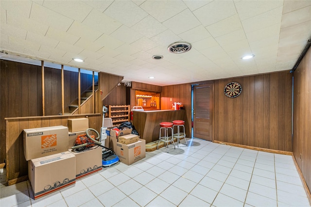 interior space featuring wooden walls, visible vents, stairs, recessed lighting, and a bar