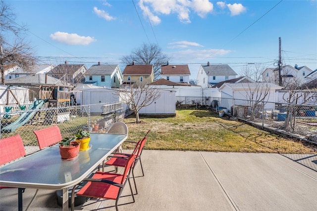 view of patio / terrace with outdoor dining space, a storage shed, a fenced backyard, and a residential view