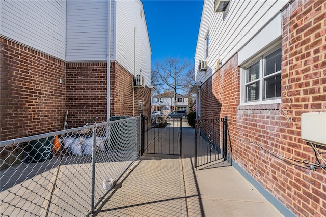 view of property exterior with a gate, fence, and brick siding