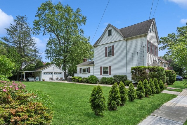 73 Spruce Ave, Floral Park, NY 11001 - view of side of property with a garage, a yard, an outdoor structure, and a shingled roof