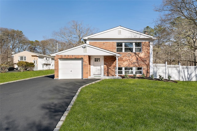 tri-level home featuring brick siding, a front lawn, fence, aphalt driveway, and a garage