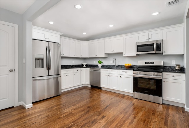 kitchen featuring dark wood-style floors, visible vents, a sink, stainless steel appliances, and white cabinets