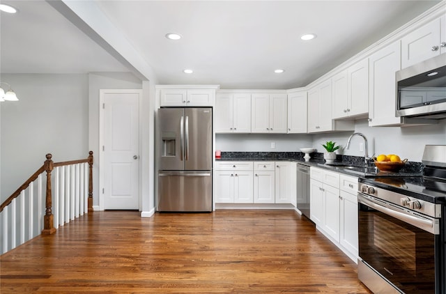 kitchen with a sink, appliances with stainless steel finishes, wood finished floors, and white cabinets