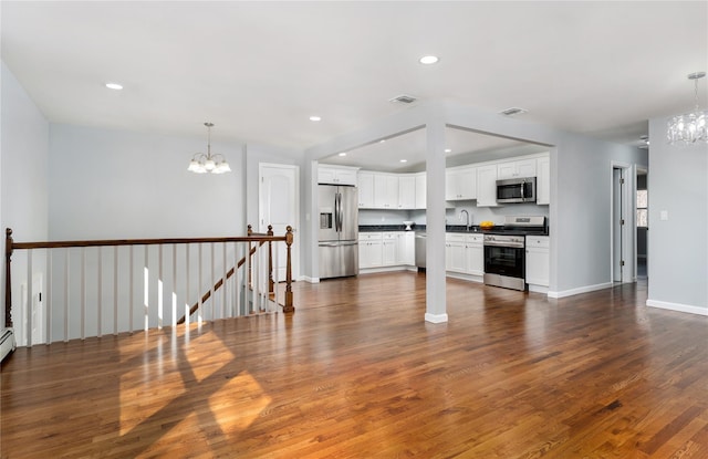 unfurnished living room featuring visible vents, recessed lighting, an inviting chandelier, and dark wood-style flooring