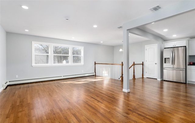 unfurnished living room featuring baseboard heating, recessed lighting, visible vents, and wood finished floors