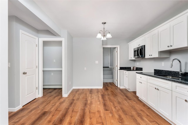 kitchen featuring a sink, stainless steel microwave, light wood-style floors, white cabinets, and a baseboard radiator