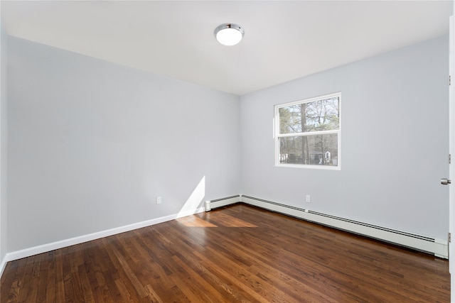 empty room featuring a baseboard heating unit, baseboards, and wood finished floors