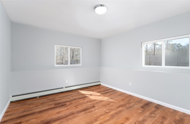 spare room with wood finished floors, baseboards, and baseboard heating