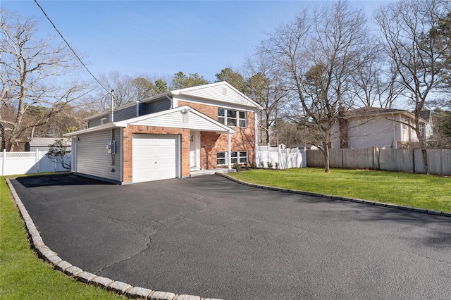 view of front of house with brick siding, an attached garage, a front yard, and fence