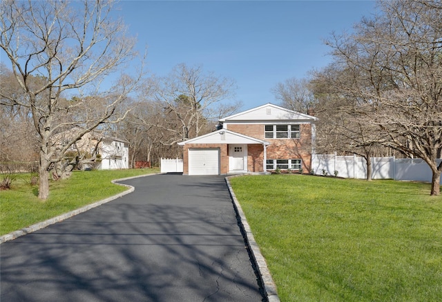 view of front of house featuring brick siding, an attached garage, a front yard, and fence