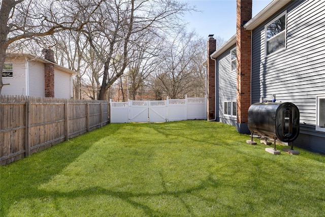 view of yard featuring a fenced backyard, heating fuel, and a gate